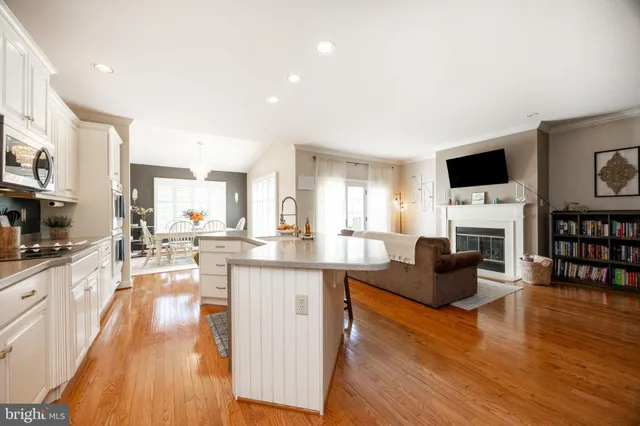a living room with furniture a fireplace a flat screen tv and a kitchen view