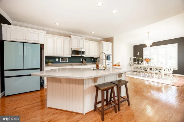 a kitchen with stainless steel appliances a stove a sink a refrigerator white cabinets and wooden floor