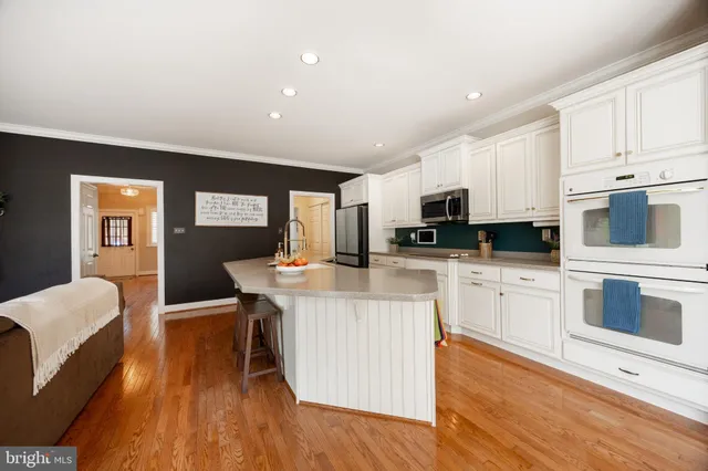 a kitchen with stainless steel appliances granite countertop a stove top oven a sink dishwasher and white cabinets with wooden floor