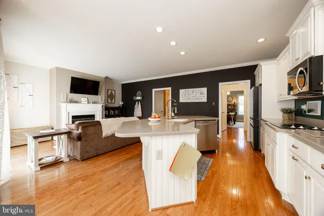 a large living room with stainless steel appliances furniture a fireplace and a flat screen tv