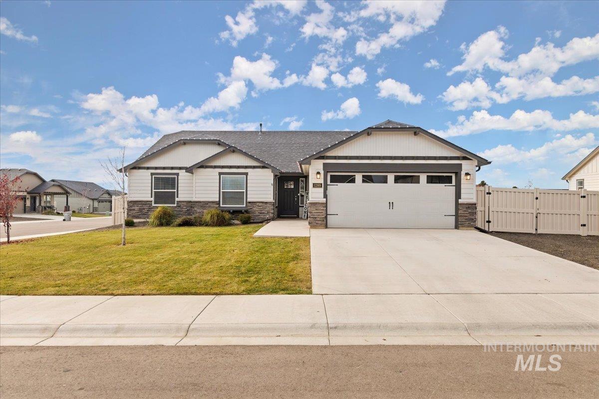 Craftsman house featuring a gate, stone siding, driveway, and an attached garage