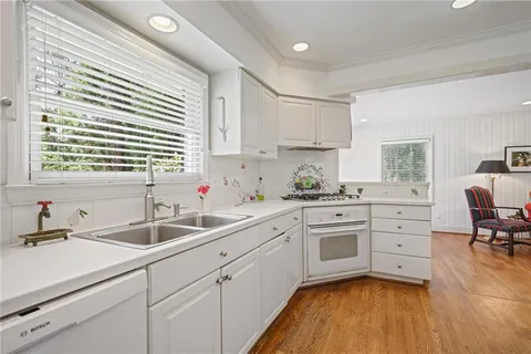 a kitchen with white cabinets sink and window