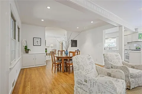a living room with furniture and a dining table with wooden floor