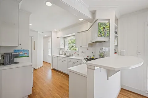 a kitchen with a sink a stove a refrigerator and white cabinets