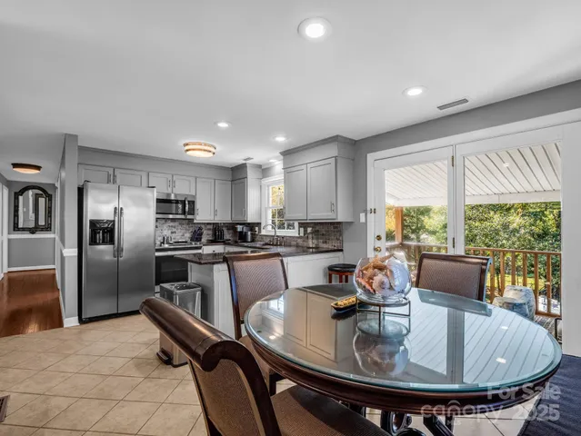 a kitchen with stainless steel appliances granite countertop sink stove and dining table chair
