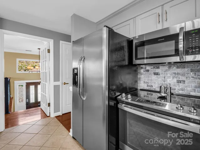 a kitchen with stainless steel appliances granite countertop a stove top oven a sink a dining table and chairs with wooden floor