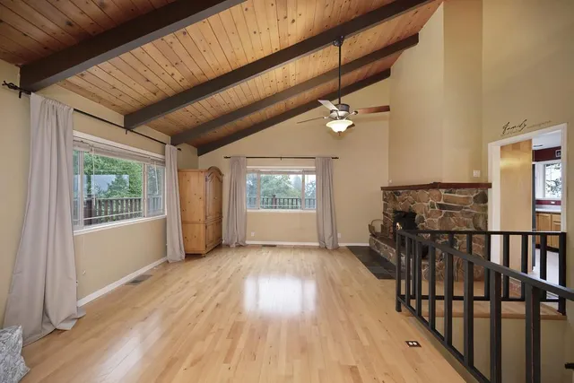 a view of an empty room with wooden floor fireplace and a window