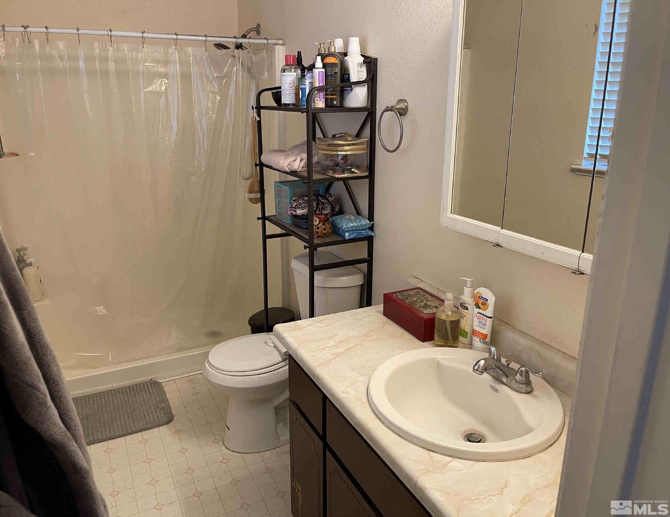 703 Empire Road Dayton, NV 89403 - Photo 14 of 31 a bathroom with a sink a toilet and shower curtain