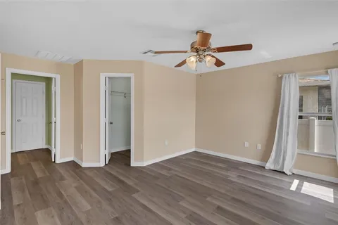 an empty room with wooden floor and a ceiling fan