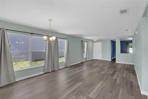 a view of an empty room with glass door and wooden floor