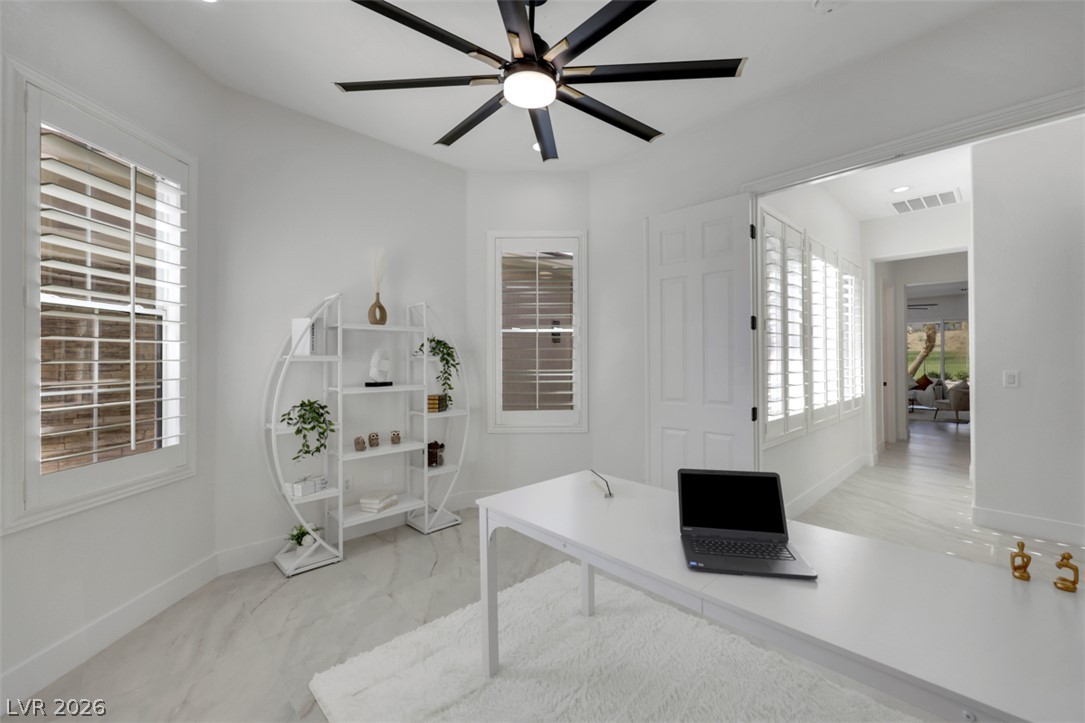5015 Rivedro Street Las Vegas, NV 89135 - Photo 43 of 91 Bright workspace illuminated by natural light through shuttered windows, featuring a sleek desk and decorative shelving.