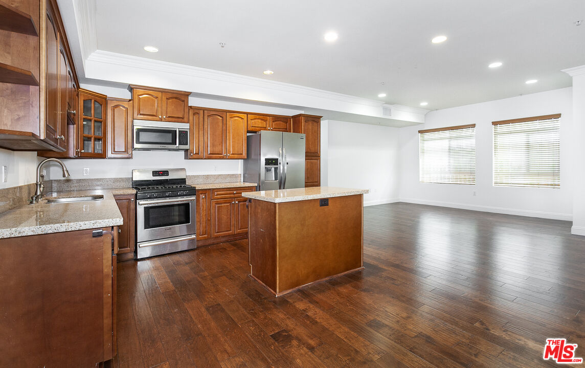 a kitchen with stainless steel appliances granite countertop a stove top oven a sink with wooden floors