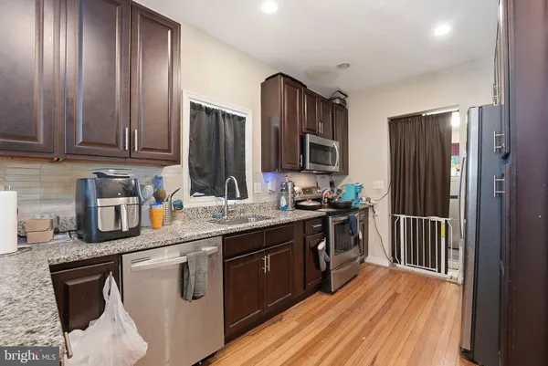 a kitchen with stainless steel appliances granite countertop a stove a sink dishwasher and a refrigerator with wooden cabinets