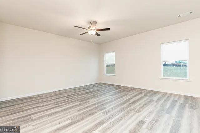 an empty room with windows and fan