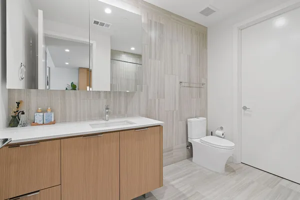 a bathroom with a granite countertop sink a toilet and a mirror