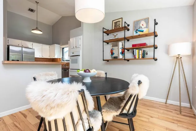 a kitchen with stainless steel appliances granite countertop a stove a sink and a dining table with wooden floor