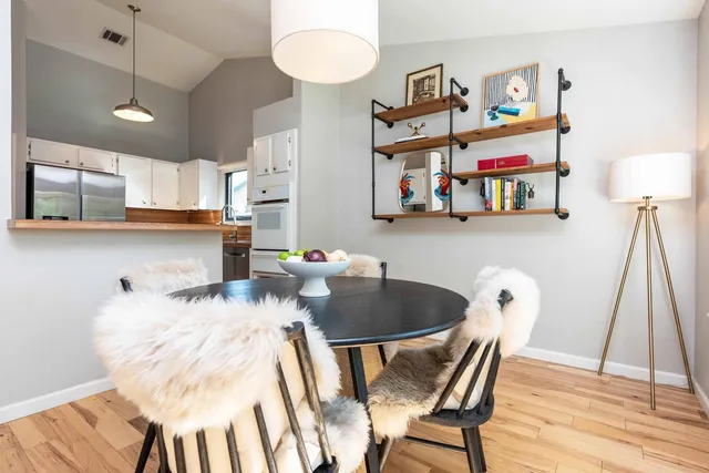 a kitchen with stainless steel appliances granite countertop a stove a sink and a dining table with wooden floor