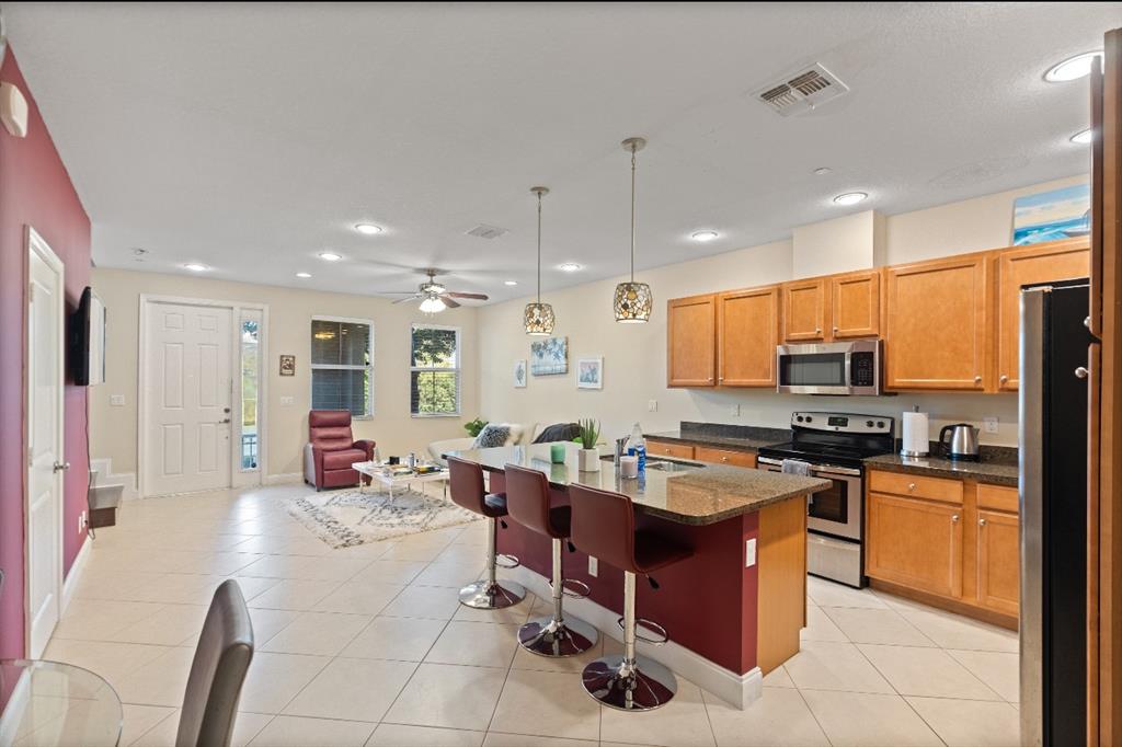 4025 Cascada Circle Hollywood, FL 33024 - Photo 3 of 19 a kitchen with stainless steel appliances granite countertop a stove top oven a sink dishwasher a dining table and chairs with wooden floor