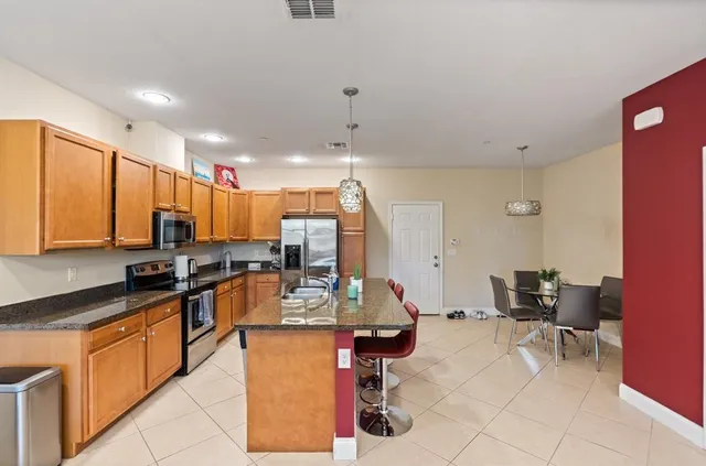 a kitchen with stainless steel appliances kitchen island granite countertop a stove a sink and a refrigerator