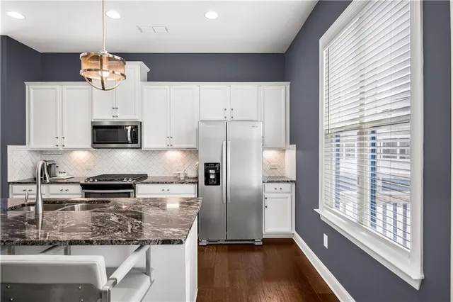 a kitchen with stainless steel appliances granite countertop a stove refrigerator a dining table and chairs with wooden floor