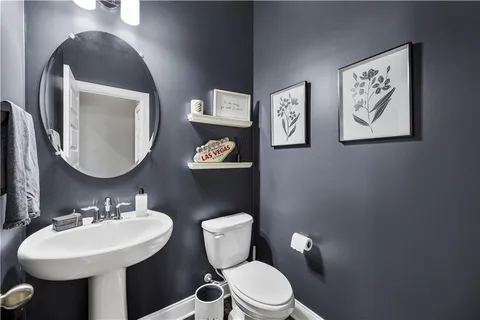 a view of a hallway with wooden floor and a bathroom
