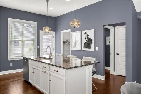 a kitchen with granite countertop a refrigerator a sink a stove and wooden cabinets