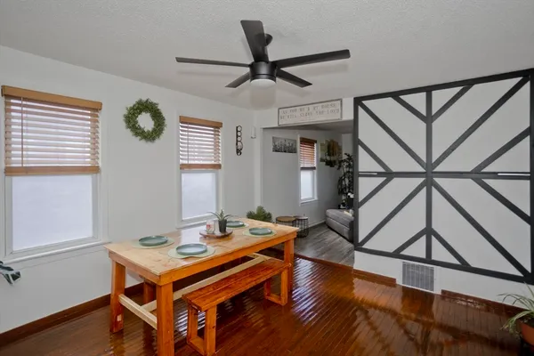 a dining room with wooden floor a chandelier a wooden table and chairs