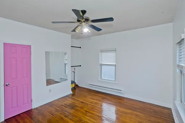 a view of empty room with wooden floor and fan