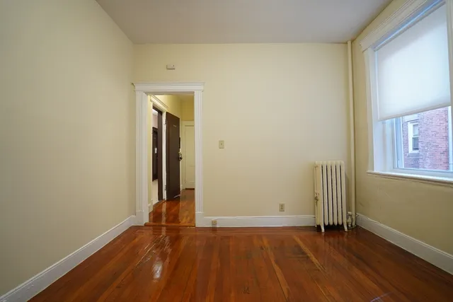 an empty room with wooden floor and a window