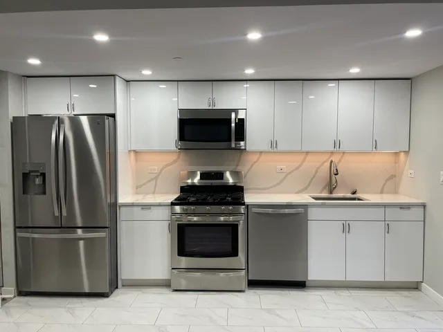a kitchen with stainless steel appliances granite countertop a refrigerator stove and sink