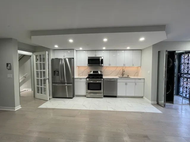 a kitchen with stainless steel appliances kitchen island granite countertop a refrigerator and a sink