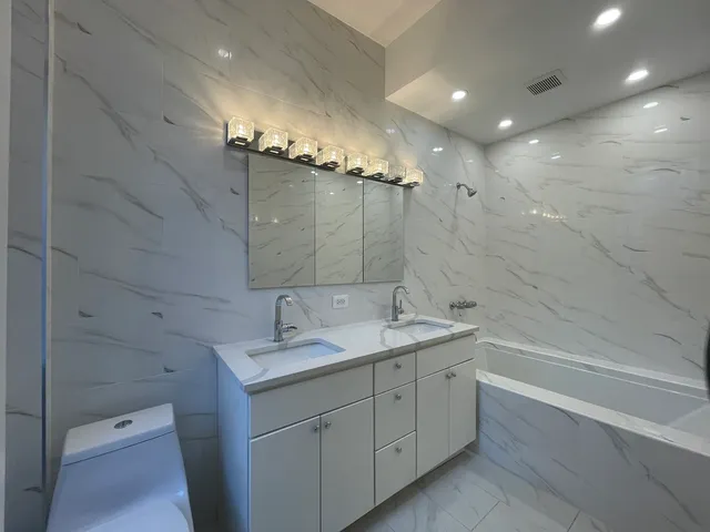 a bathroom with a granite countertop sink a toilet a mirror and shower