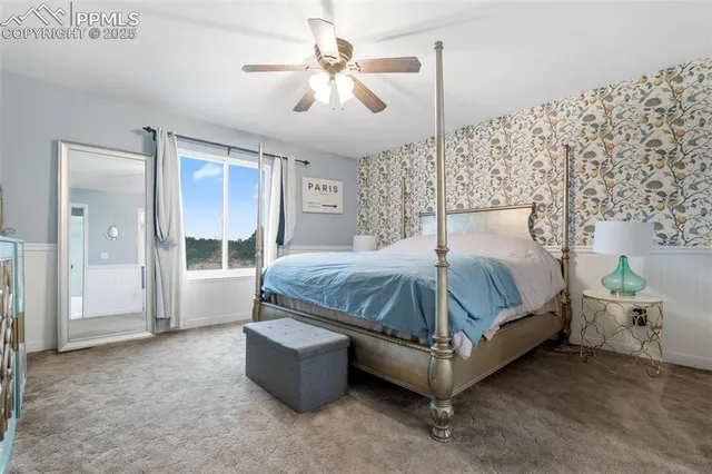 a bedroom with a large bed and a chandelier fan