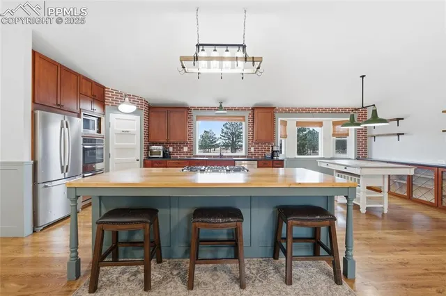 a kitchen with stainless steel appliances granite countertop a table chairs and wooden floor