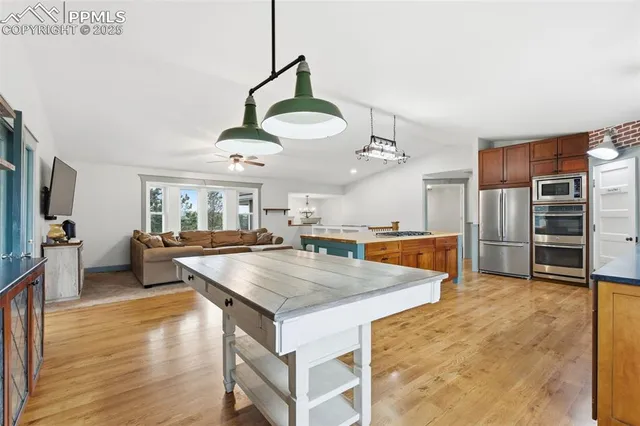 a living room with stainless steel appliances kitchen island granite countertop a table chairs and a refrigerator