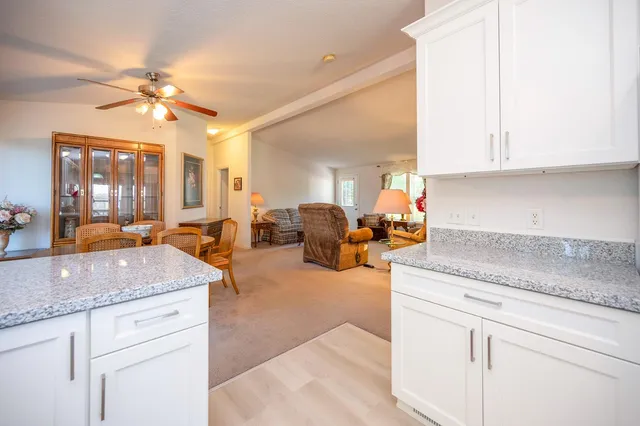 a kitchen with stainless steel appliances granite countertop a refrigerator a sink dishwasher and white cabinets with wooden floor