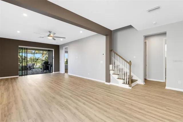 an empty room with wooden floor fan and windows