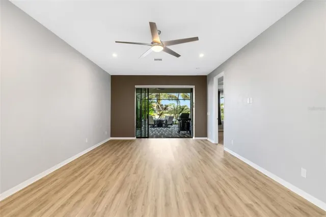 a view of an empty room with wooden floor and a kitchen