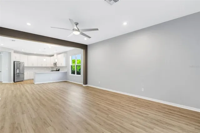 an empty room with ceiling fan and windows