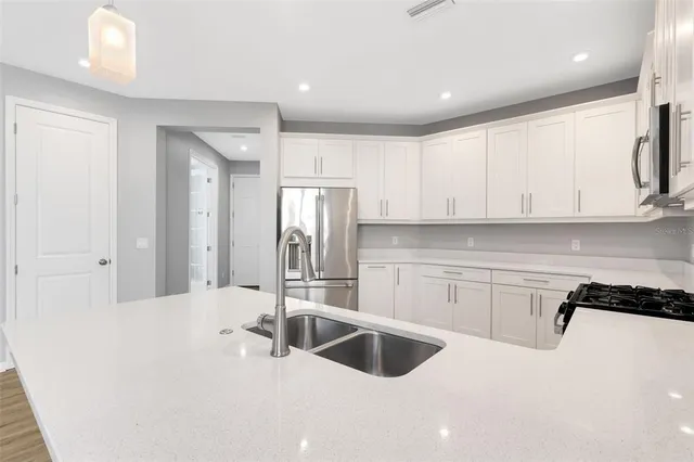 a kitchen with stainless steel appliances kitchen island granite countertop a stove a sink and white cabinets