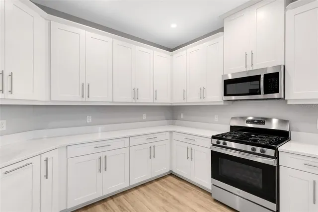 a kitchen with stainless steel appliances white cabinets a sink and a stove