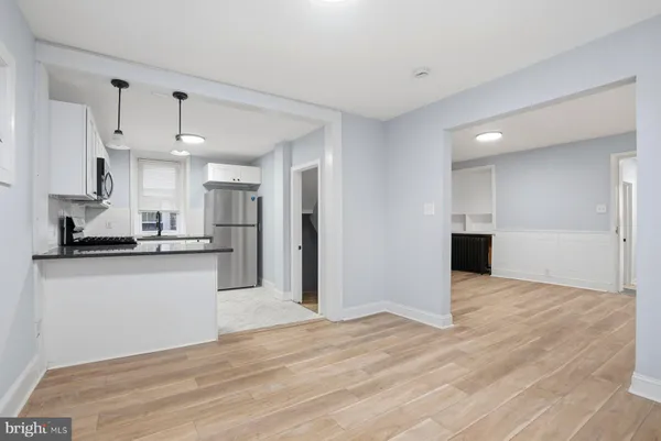 a view of a kitchen with kitchen island a sink wooden floor and stainless steel appliances