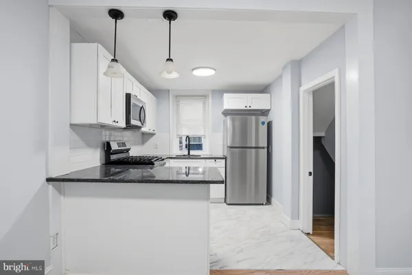 a kitchen with stainless steel appliances granite countertop a refrigerator a sink dishwasher a stove and white cabinets with wooden floor