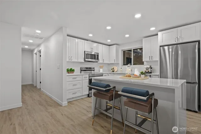 a kitchen with kitchen island white cabinets and stainless steel appliances