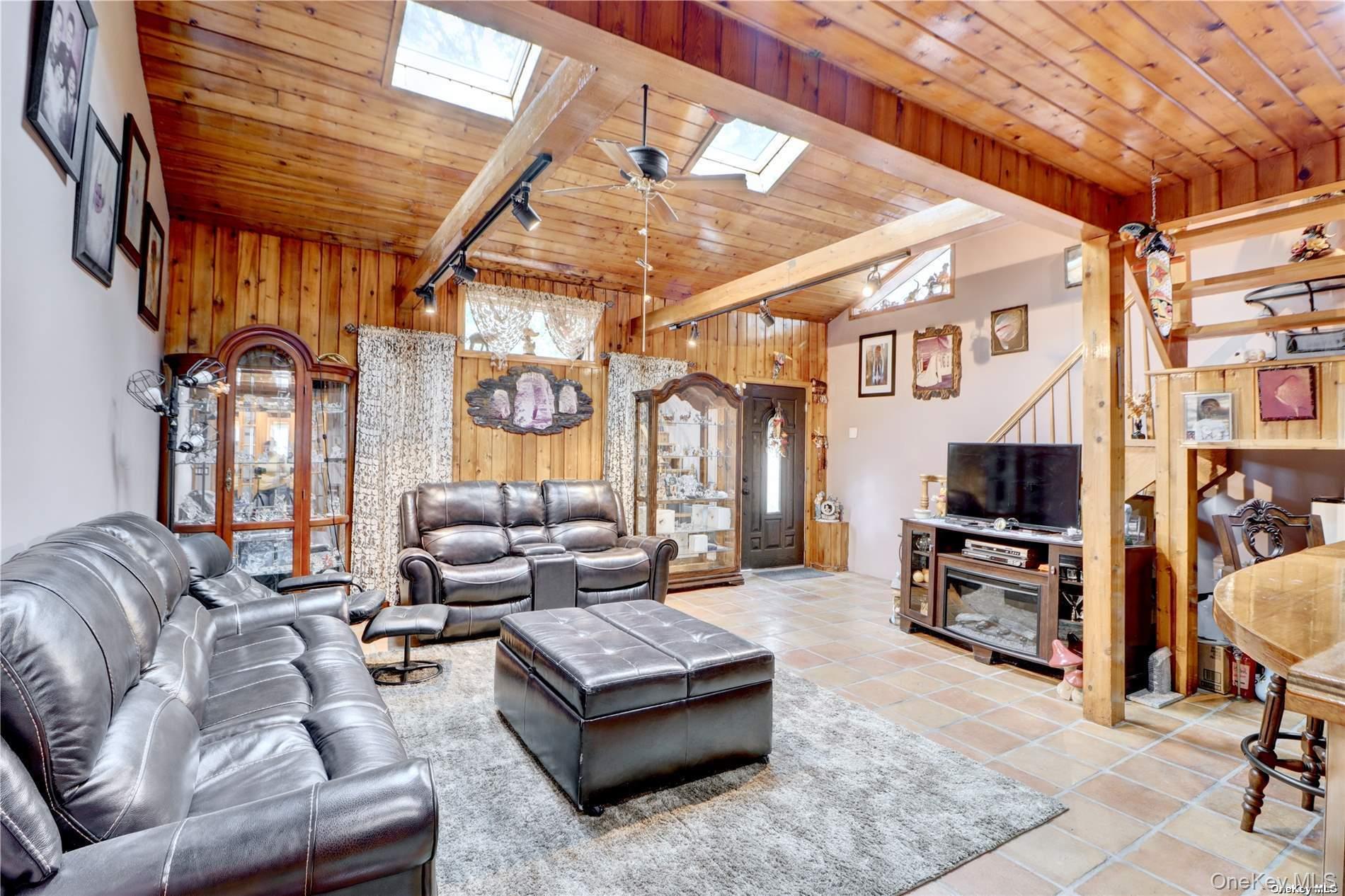 338 Cold Spring Road Syosset, NY 11791 - Photo 5 of 22 Living area featuring wooden walls, wood ceiling, a skylight, stairs, and tile patterned floors