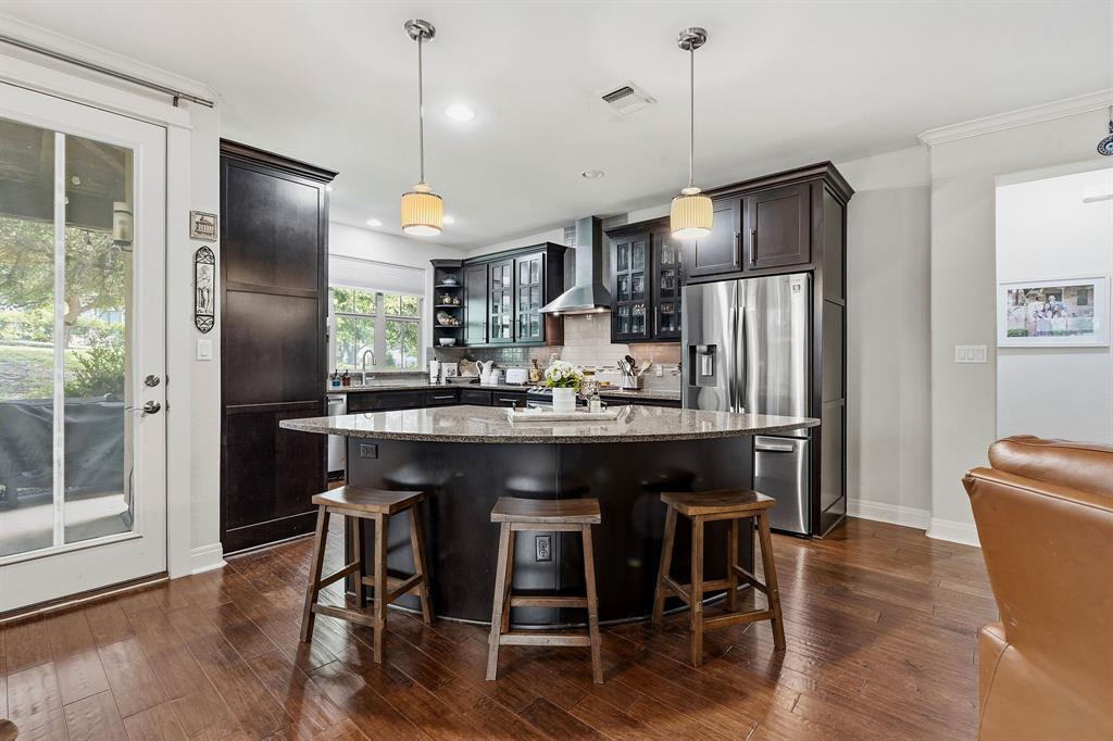15317 Falconhead Grove Loop Austin, TX 78738 - Photo 2 of 29 A well-appointed kitchen features rich cabinetry, granite countertops, and gleaming hardwood floors.