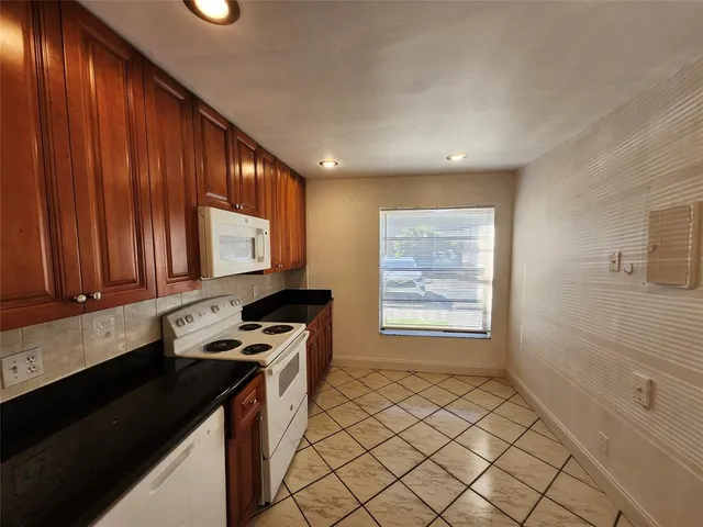 a kitchen with granite countertop a sink stove and cabinets