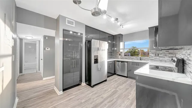 a large kitchen with stainless steel appliances kitchen island a large counter top a sink a stove and a refrigerator