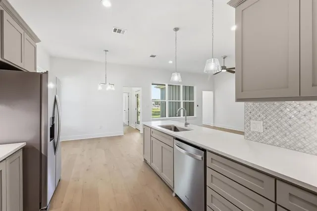 a large room with kitchen island a chandelier and wooden floor