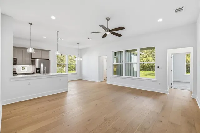 a view of an empty room with a window and wooden floor